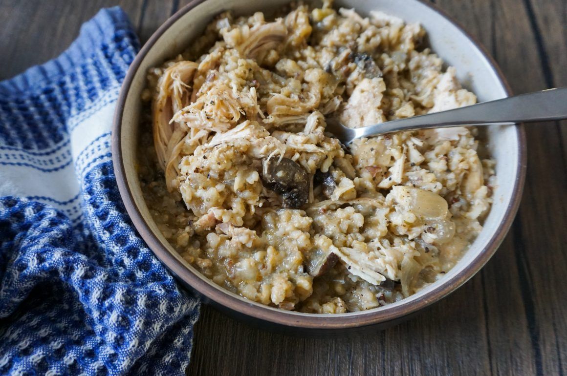 Bowl of creamy rice topped with shredded garnish beside a blue cloth on a wooden table