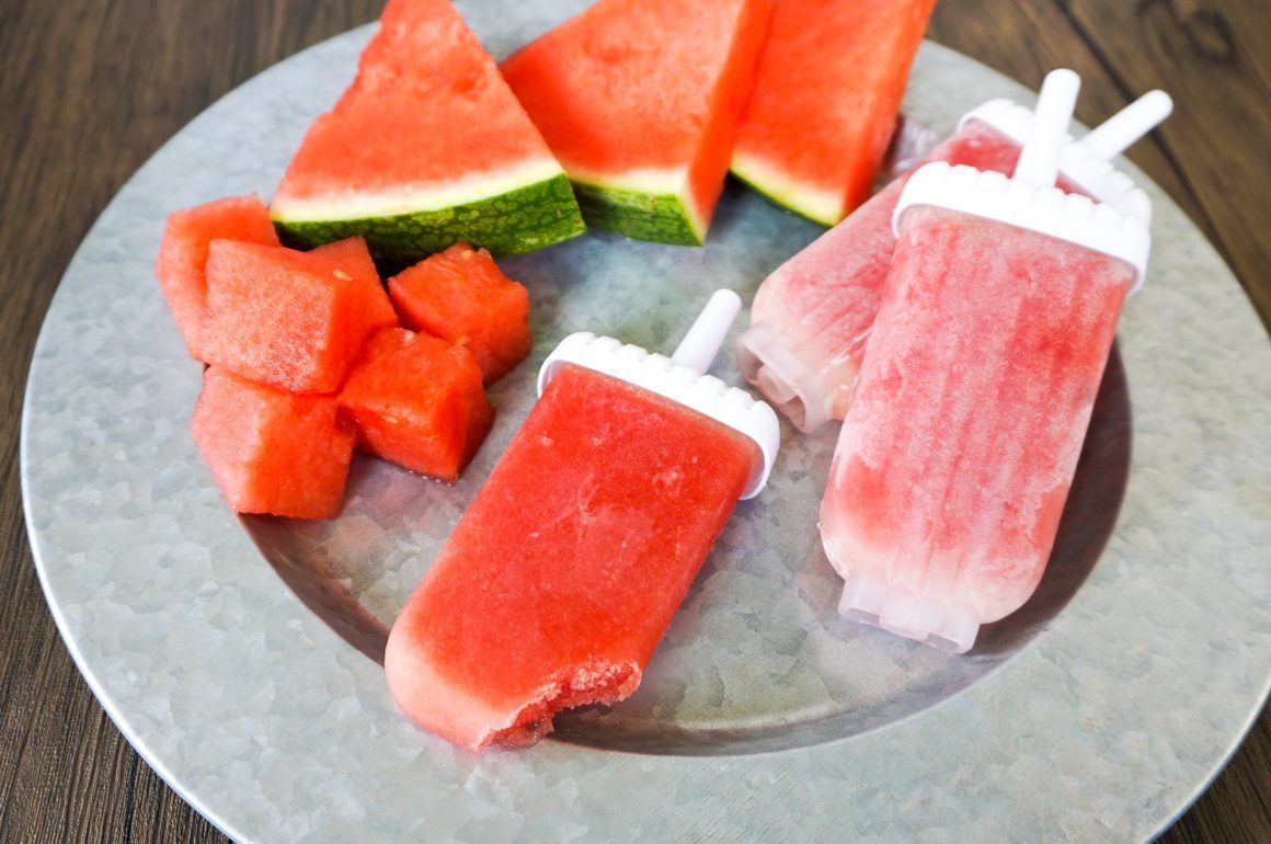 Watermelon popsicles and fresh watermelon slices on a metal plate