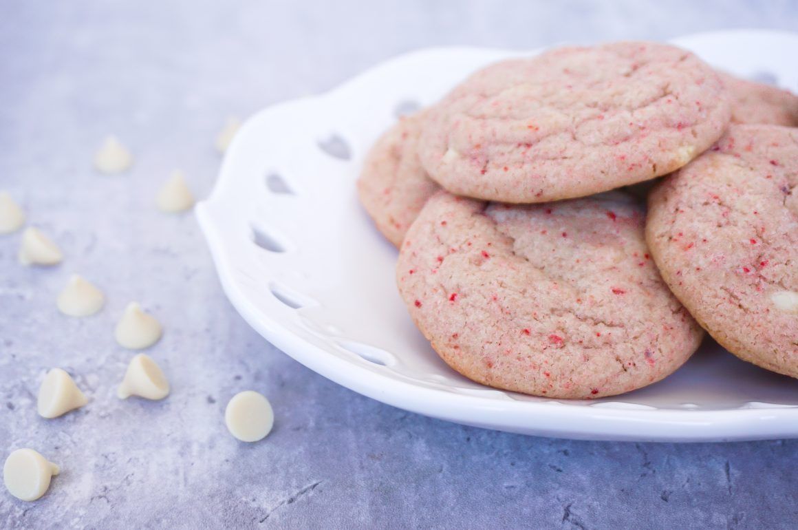 Plate of pink sugar cookies with white chocolate chips on a blue surface