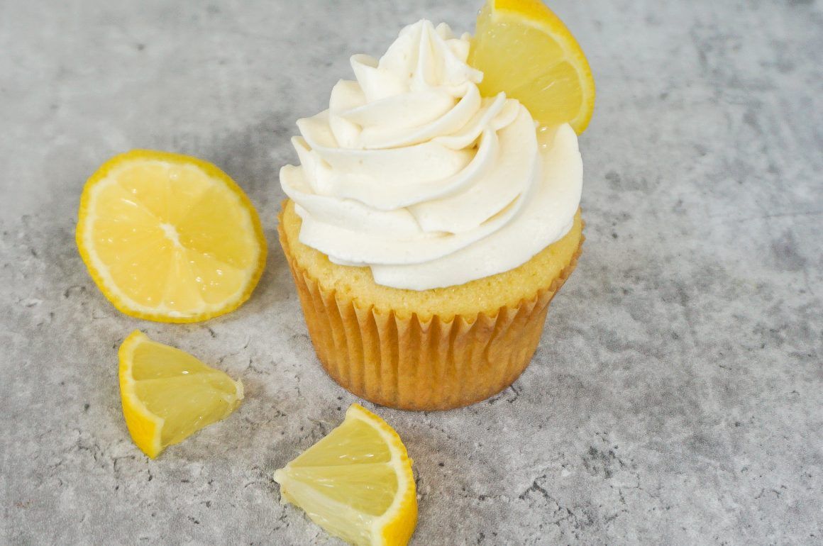 Lemon cupcake with white frosting and lemon slices on a gray surface