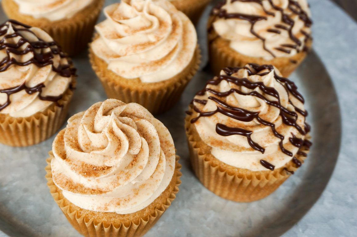 Cupcakes with swirled frosting and chocolate drizzle on a gray plate