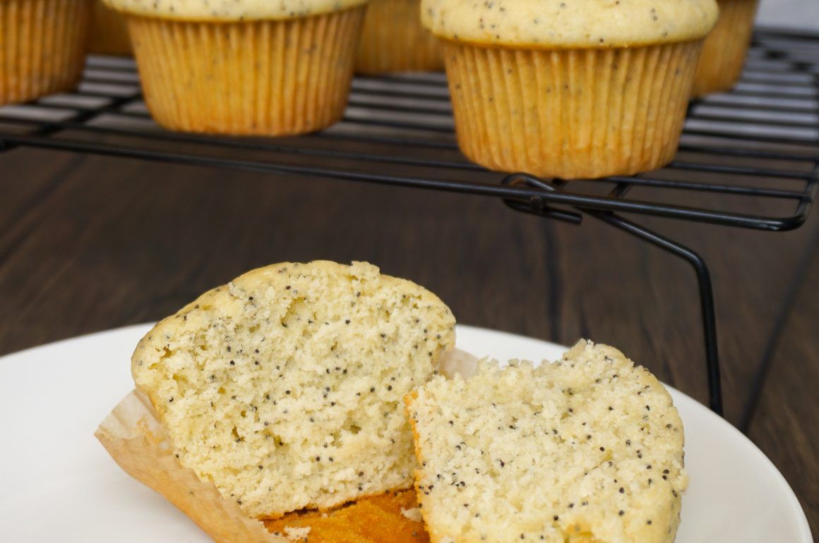 Poppy seed muffins on a plate, with more cooling on a rack in the background