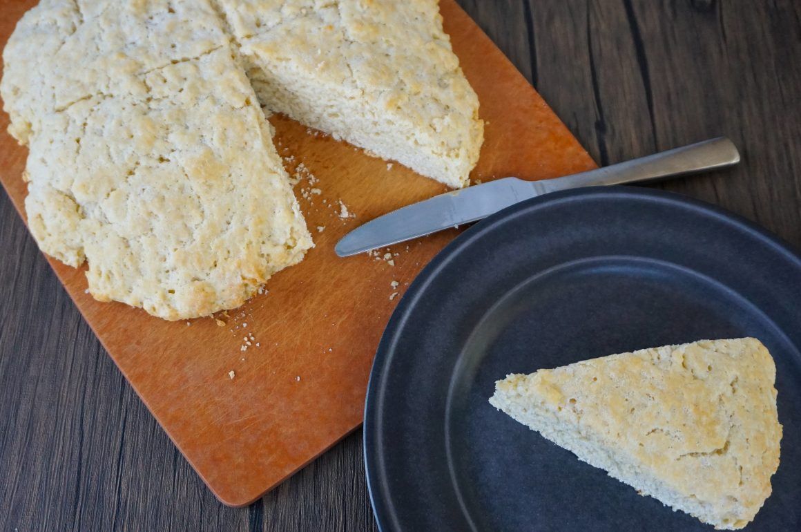 Sliced wedge of crumbly cheese or cake on a cutting board with a knife and plate.