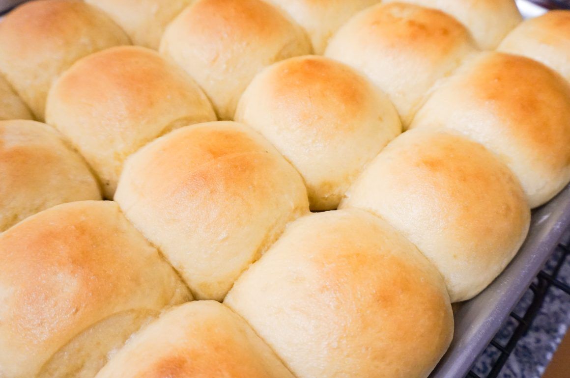 Freshly baked golden dinner rolls in a tray, close-up view