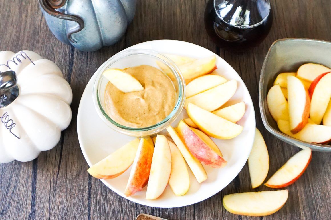 Halloween pumpkins, sliced apples, and caramel dip on a rustic table