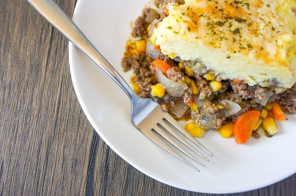 Shepherd’s pie on a white plate with a fork on a wooden table