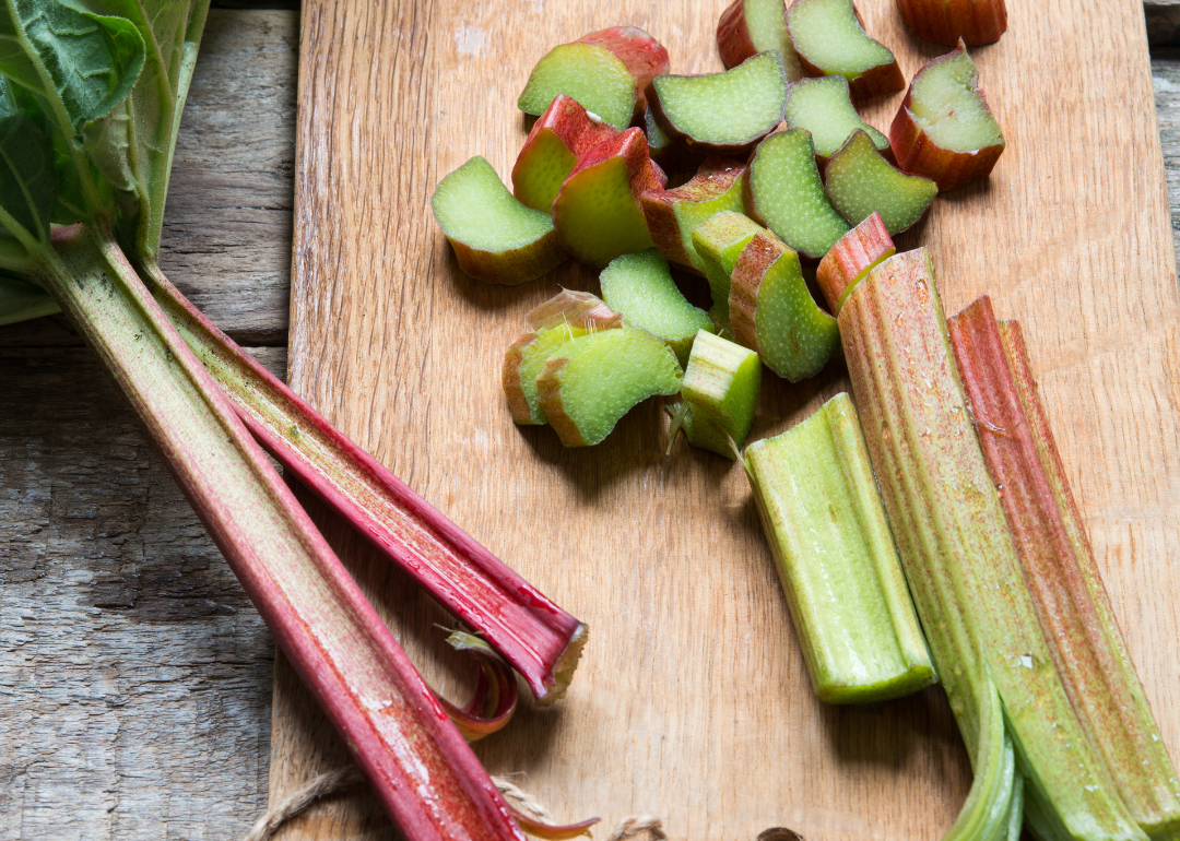 Rhubarb stalks and chopped pieces on a wooden cutting board