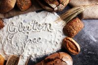Flour-dusted gluten-free baking scene with cookies, cinnamon, and a wheat stalk on a rustic table
