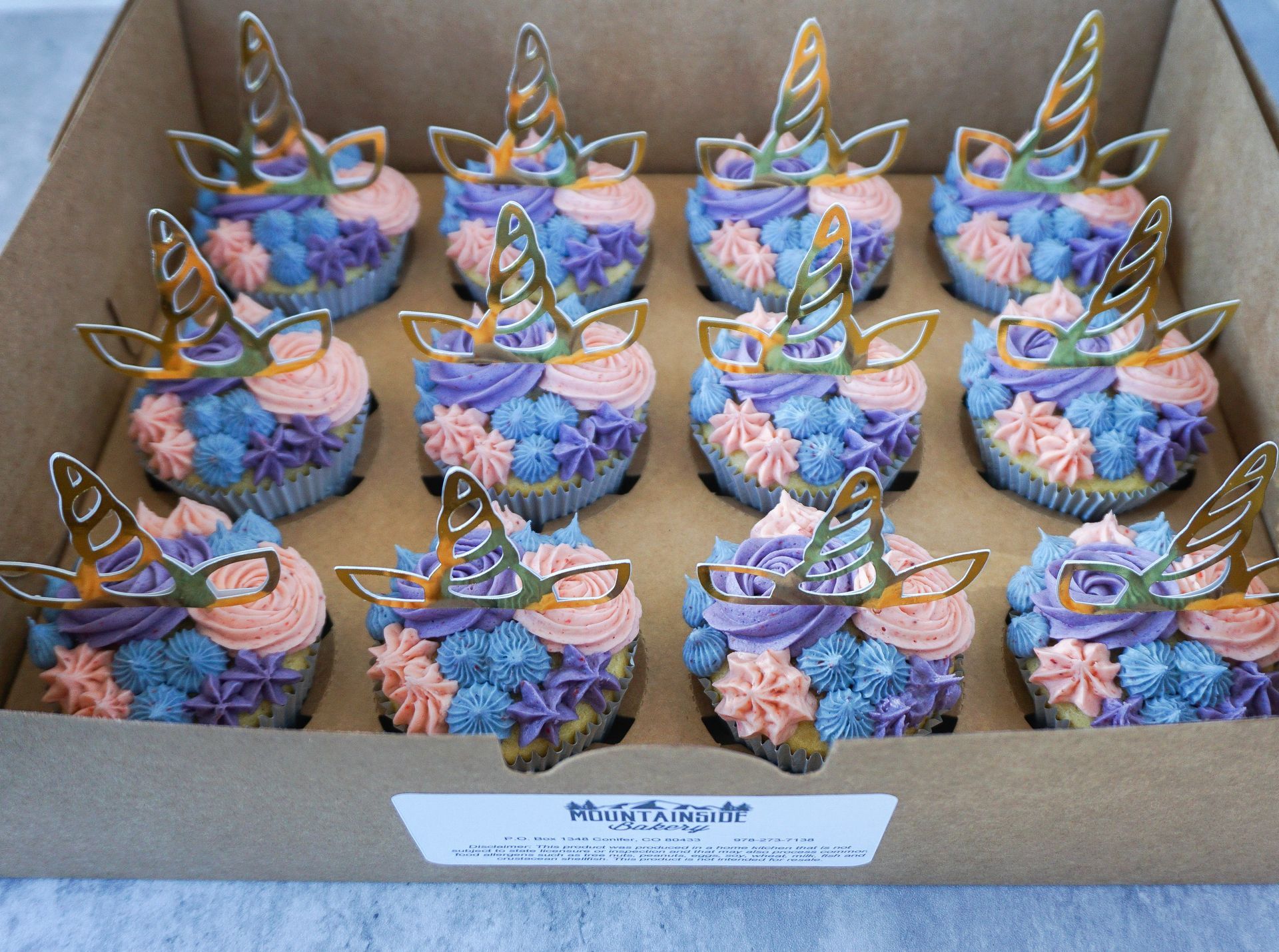 Assorted colorful butterfly-shaped decorated dessert cups arranged in a cardboard tray