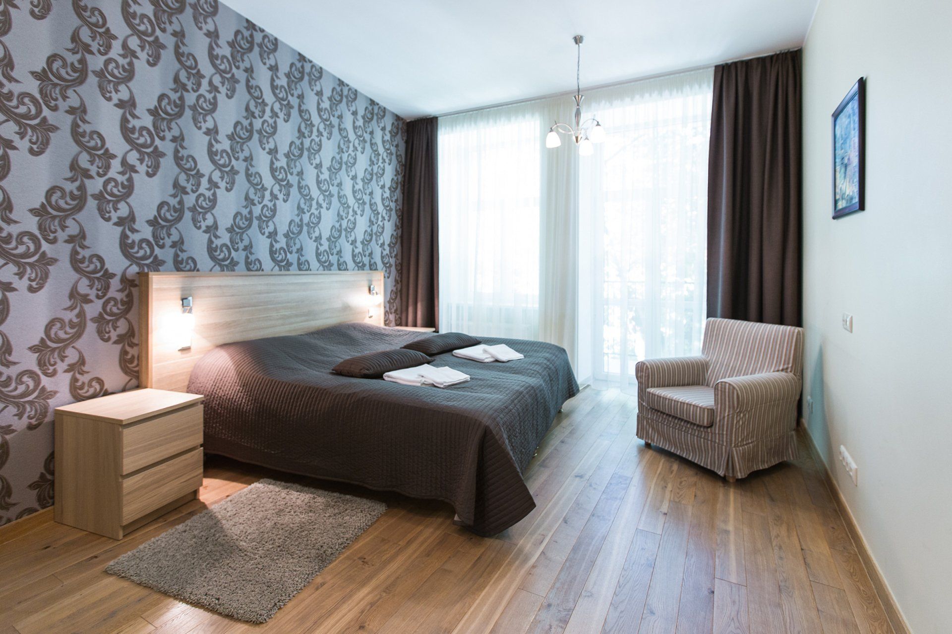 A bedroom with two beds , a chair , a nightstand and a rug.
