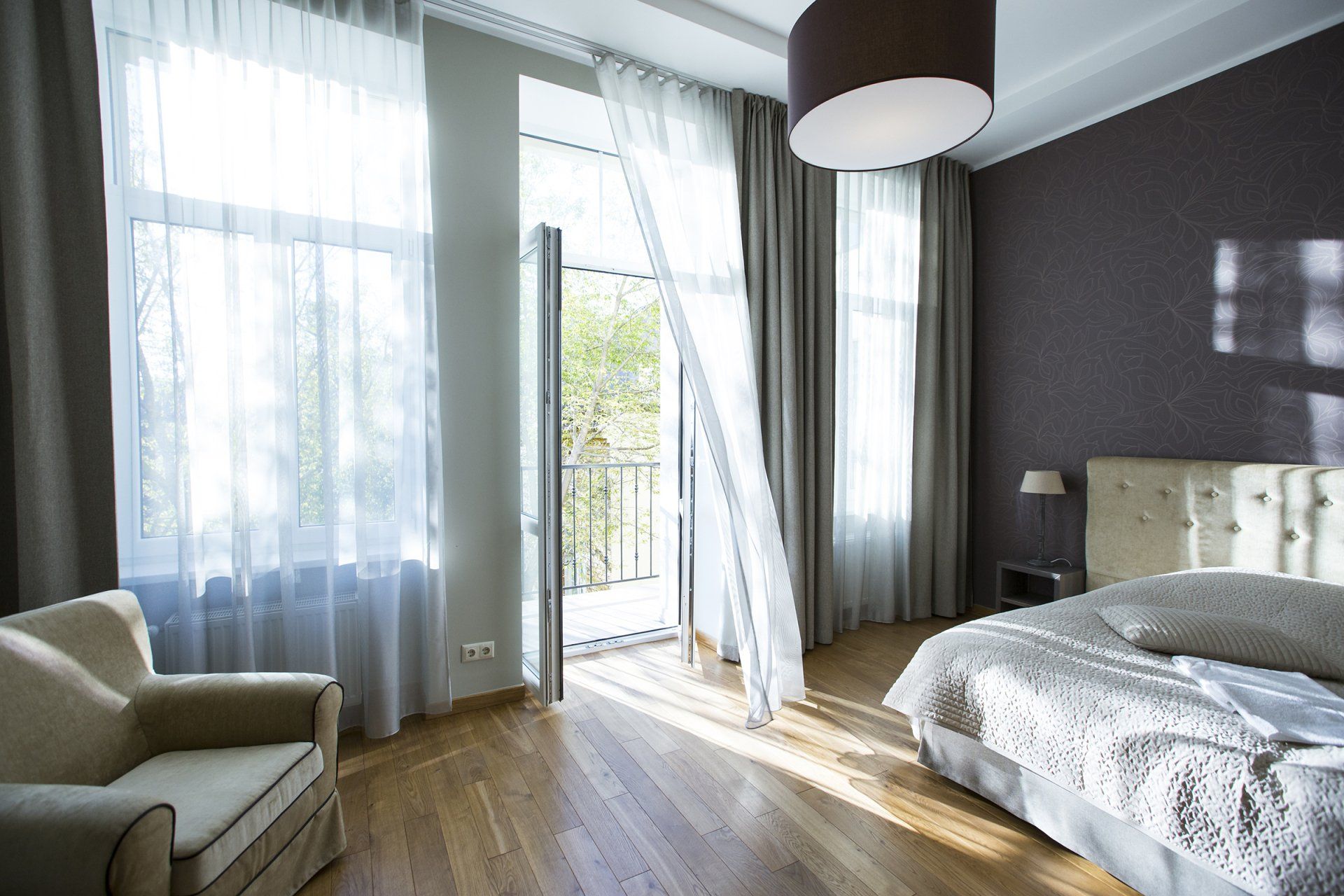 A bedroom with a bed a chair and a balcony