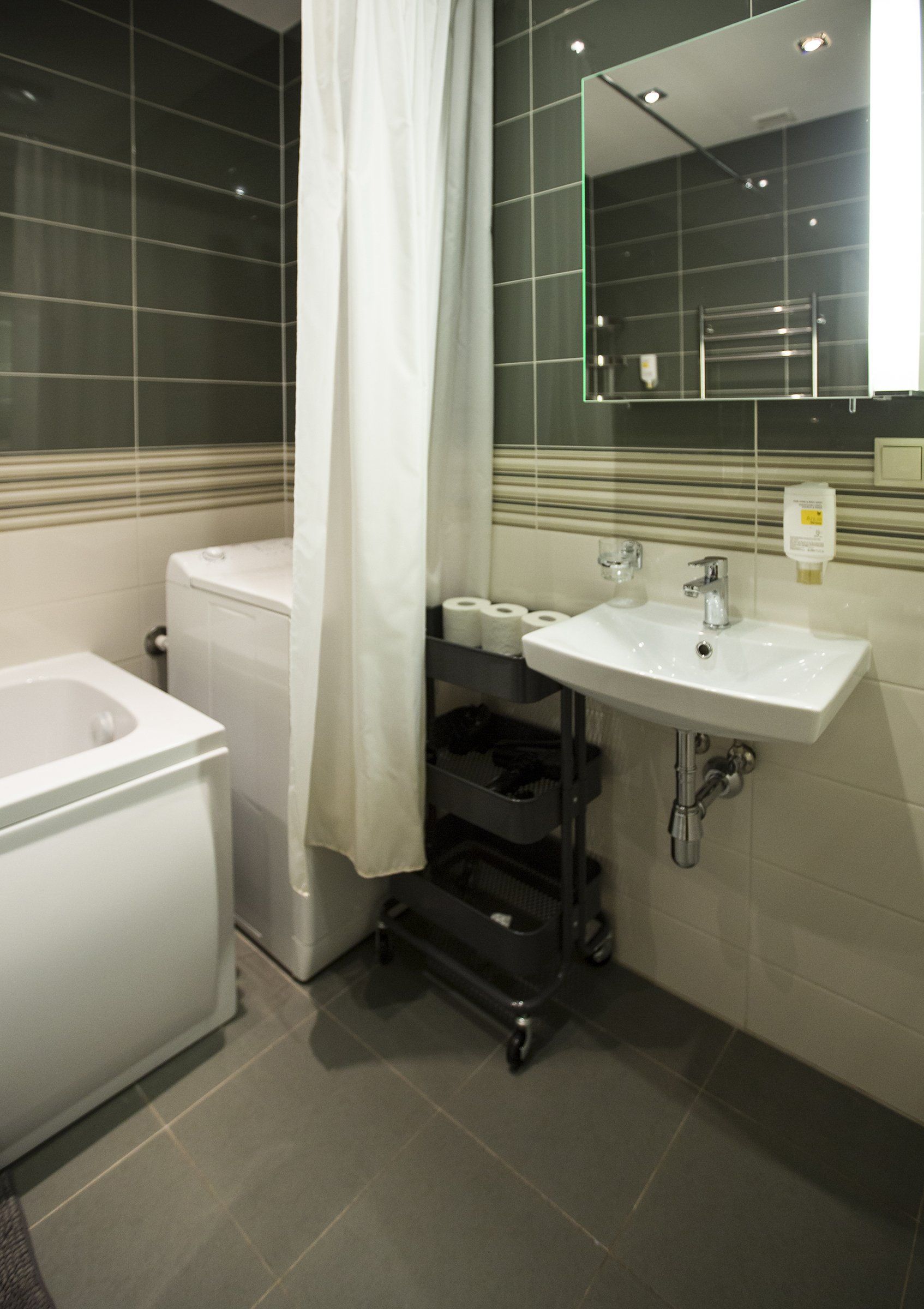 A bathroom with a tub , sink , mirror and shower curtain.