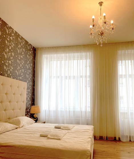 A bedroom with a large bed and a chandelier hanging from the ceiling.