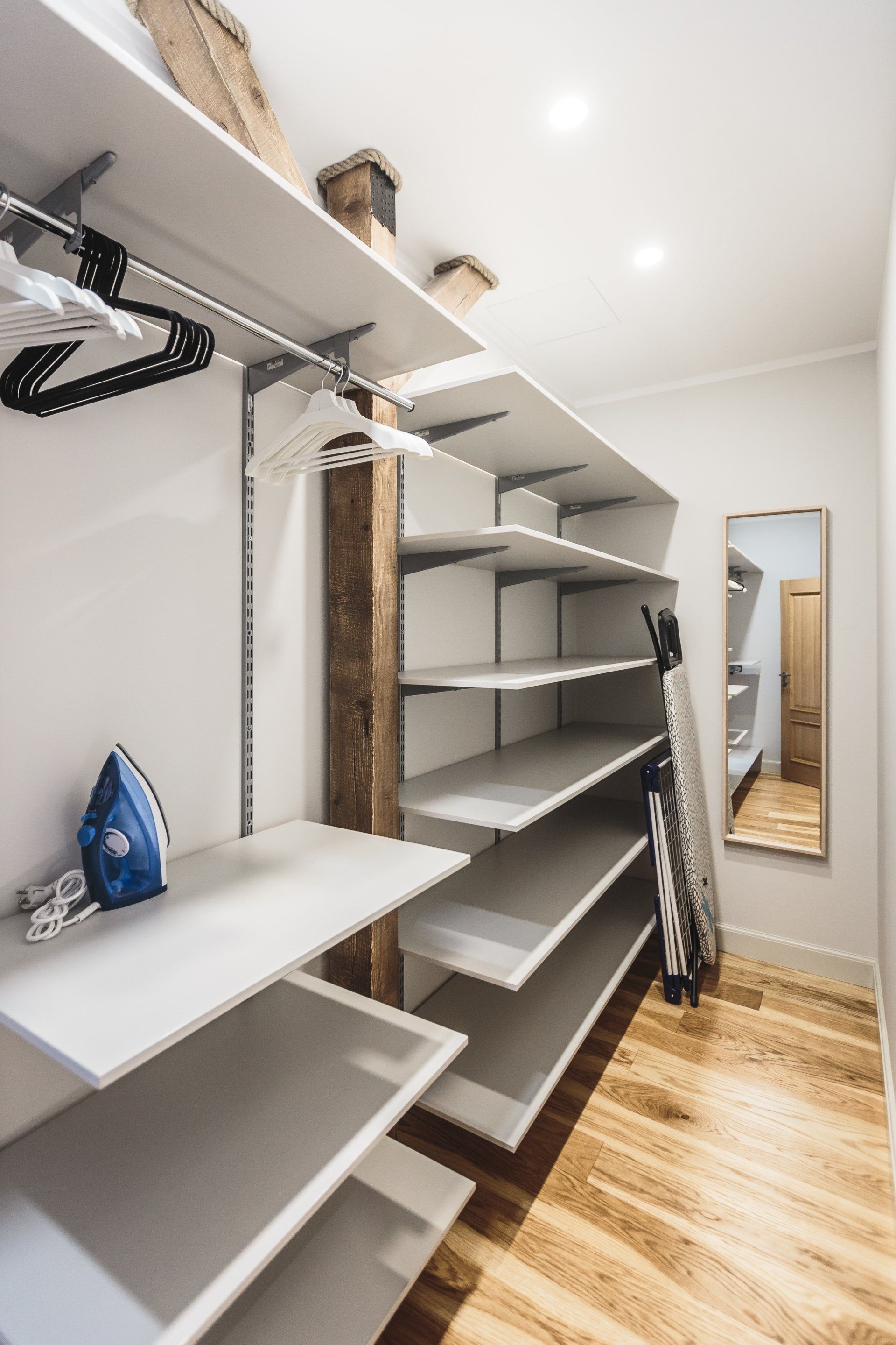 A walk in closet with empty shelves and a mirror.