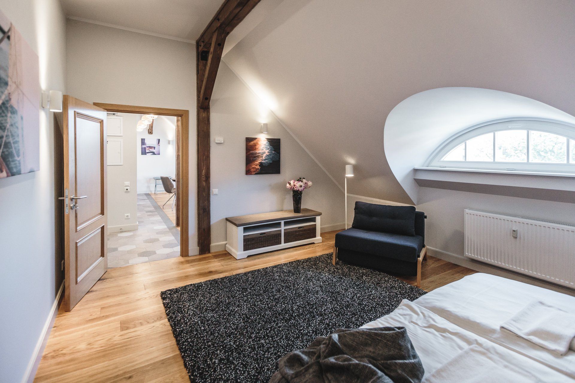 A bedroom with a bed , chair , rug and a window.