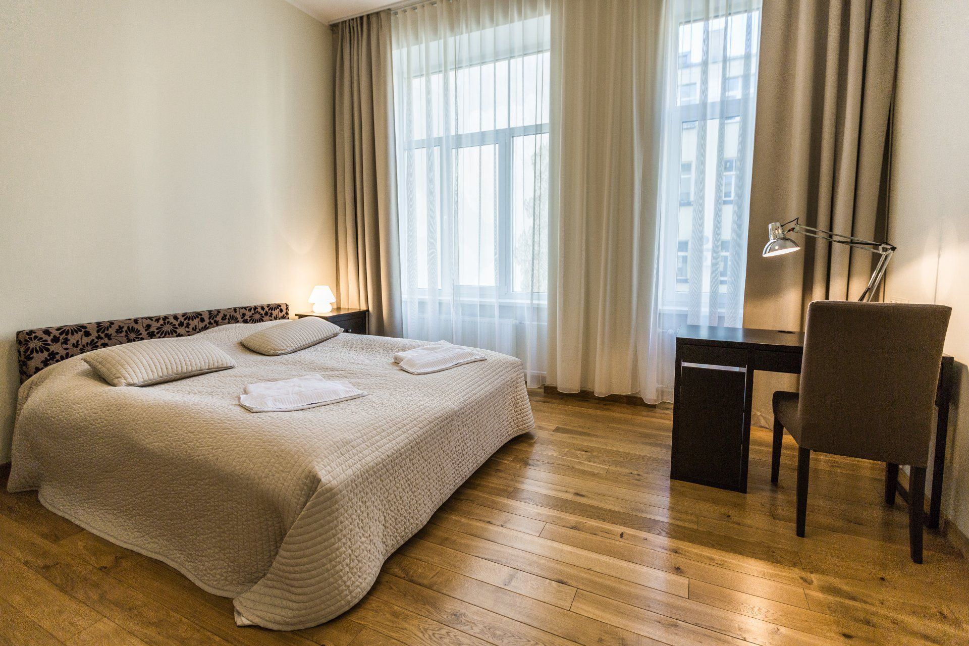 A bedroom with a bed , desk , chair and window.
