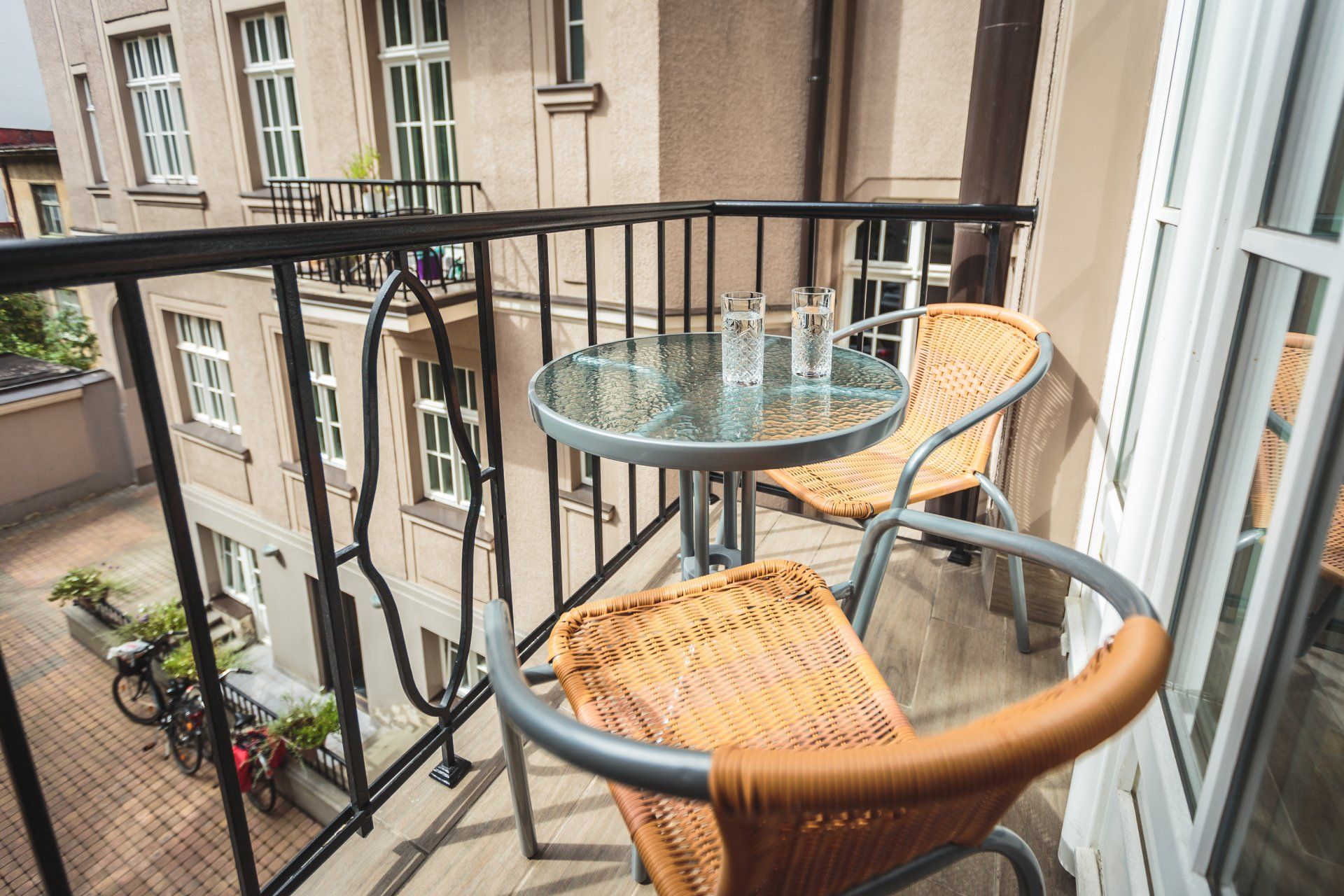 A balcony with two chairs and a table with glasses on it.