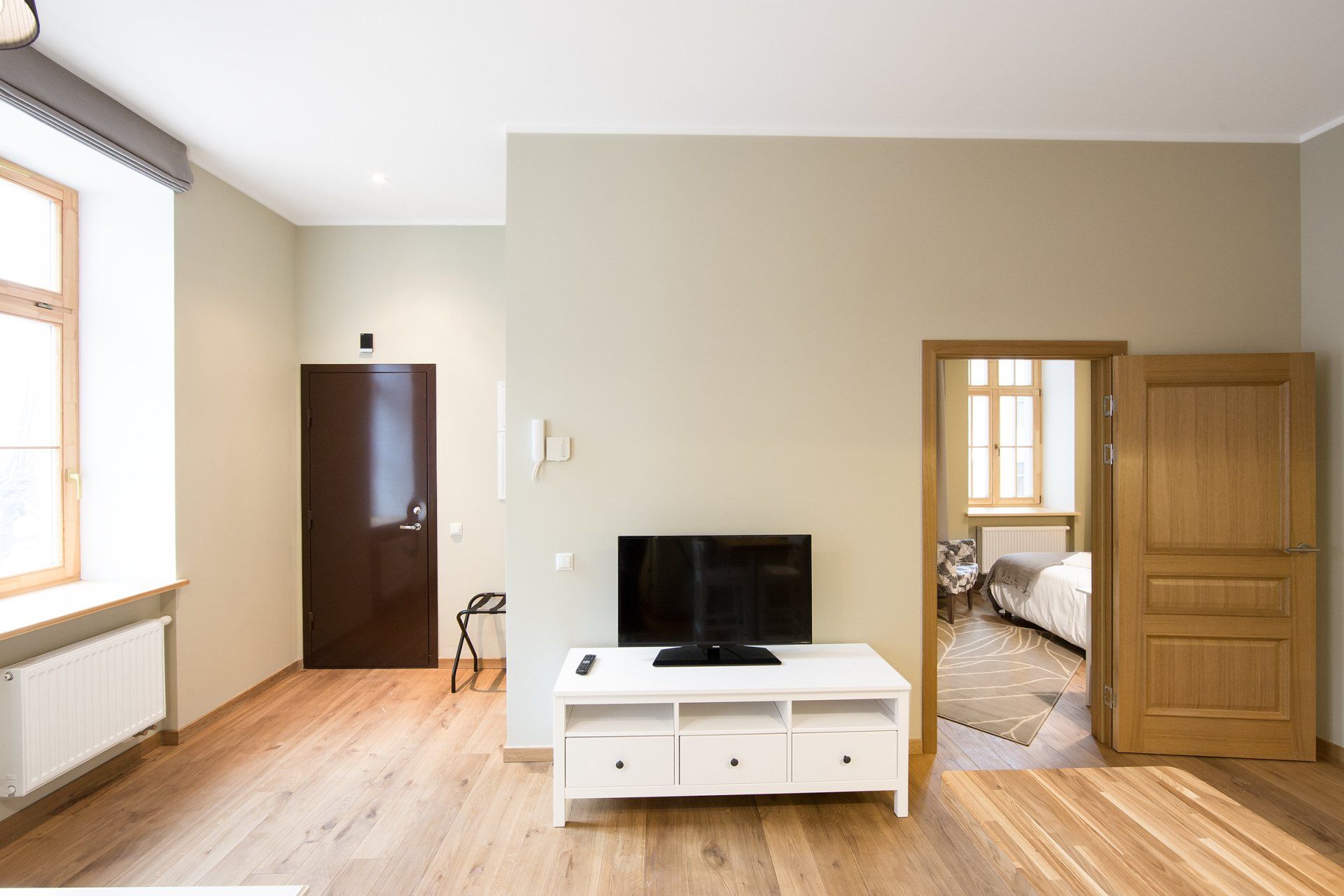 A living room with a flat screen tv on a white stand.