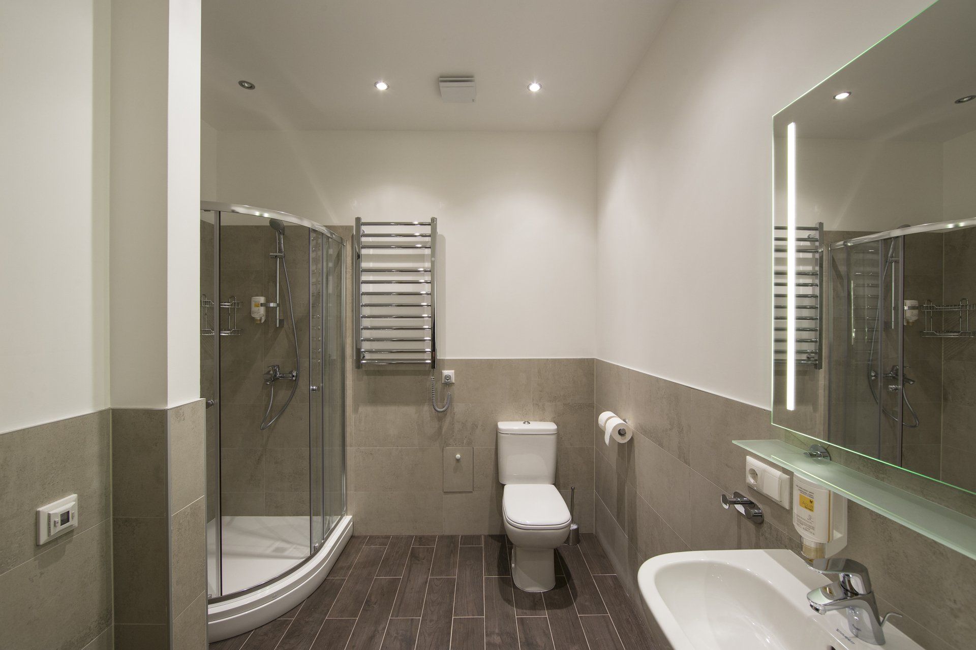 A bathroom with a toilet , sink , shower and mirror.