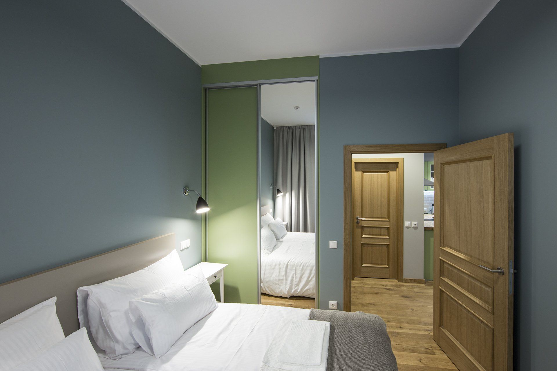 A bedroom with a king size bed and a sliding door between the bedroom and the kitchen.