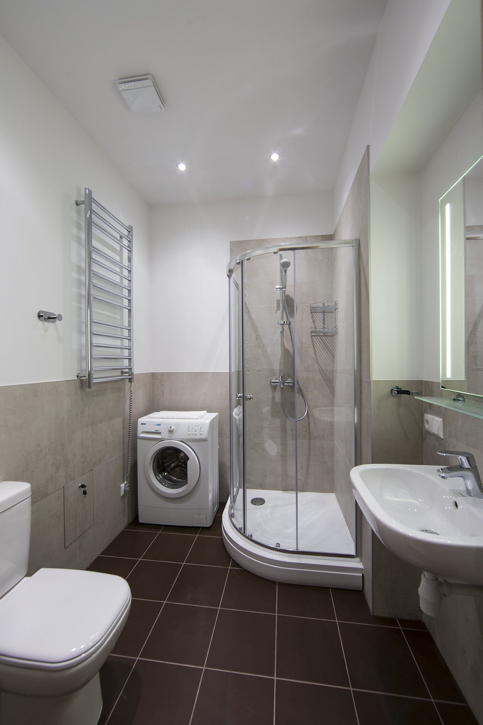 A bathroom with a toilet , sink , washer and dryer.