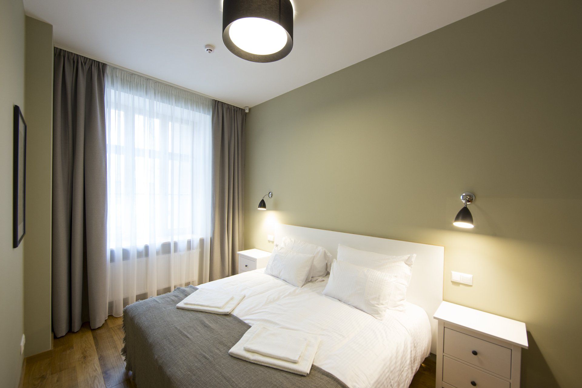 A bedroom with a bed , nightstands , curtains and a window.
