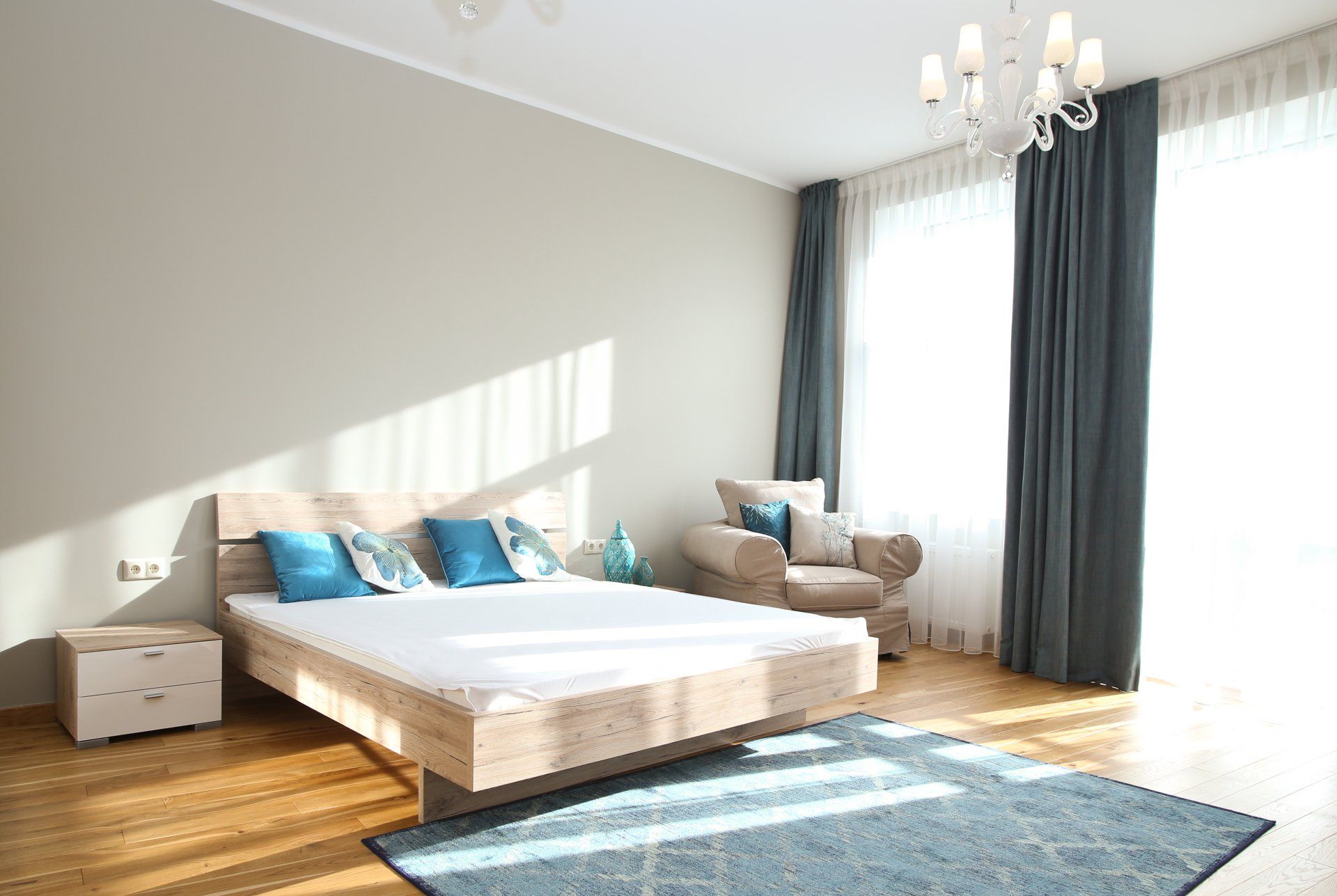 A bedroom with a bed , chair , nightstand and rug.