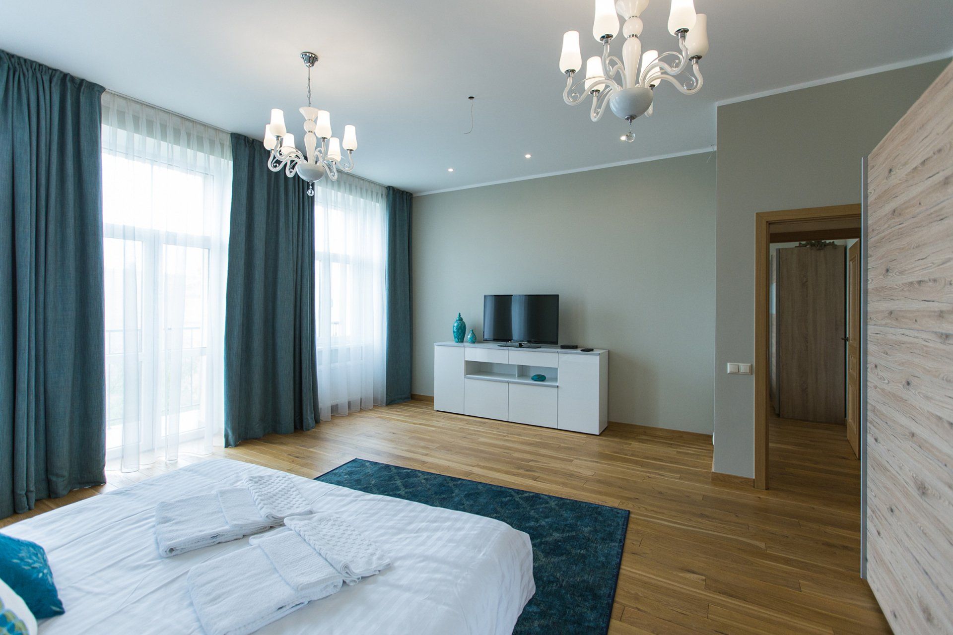 A bedroom with a bed , television , and chandelier.