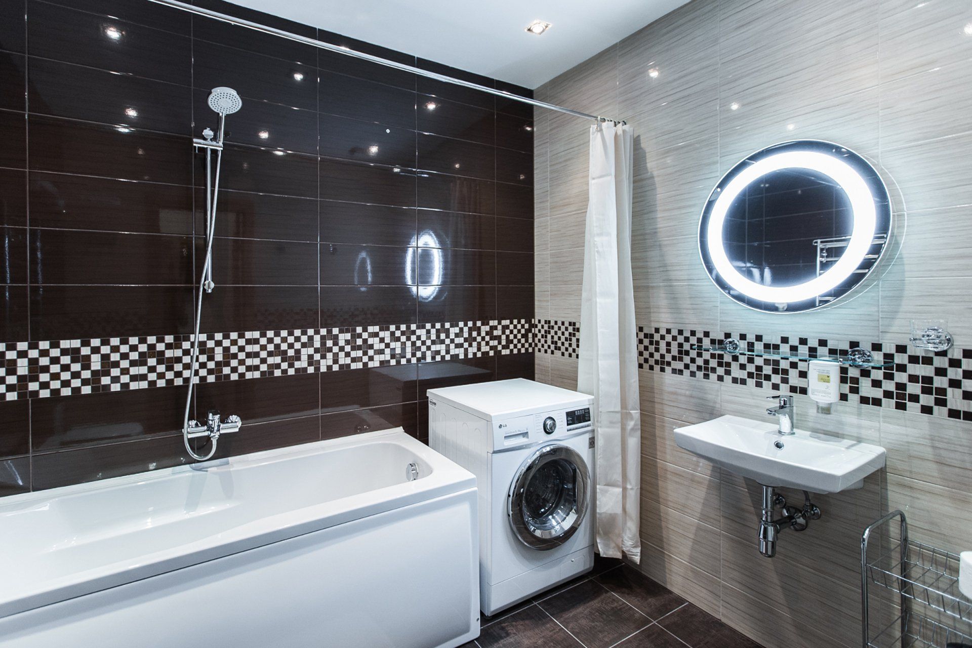 A bathroom with a bathtub , washing machine , sink and mirror.