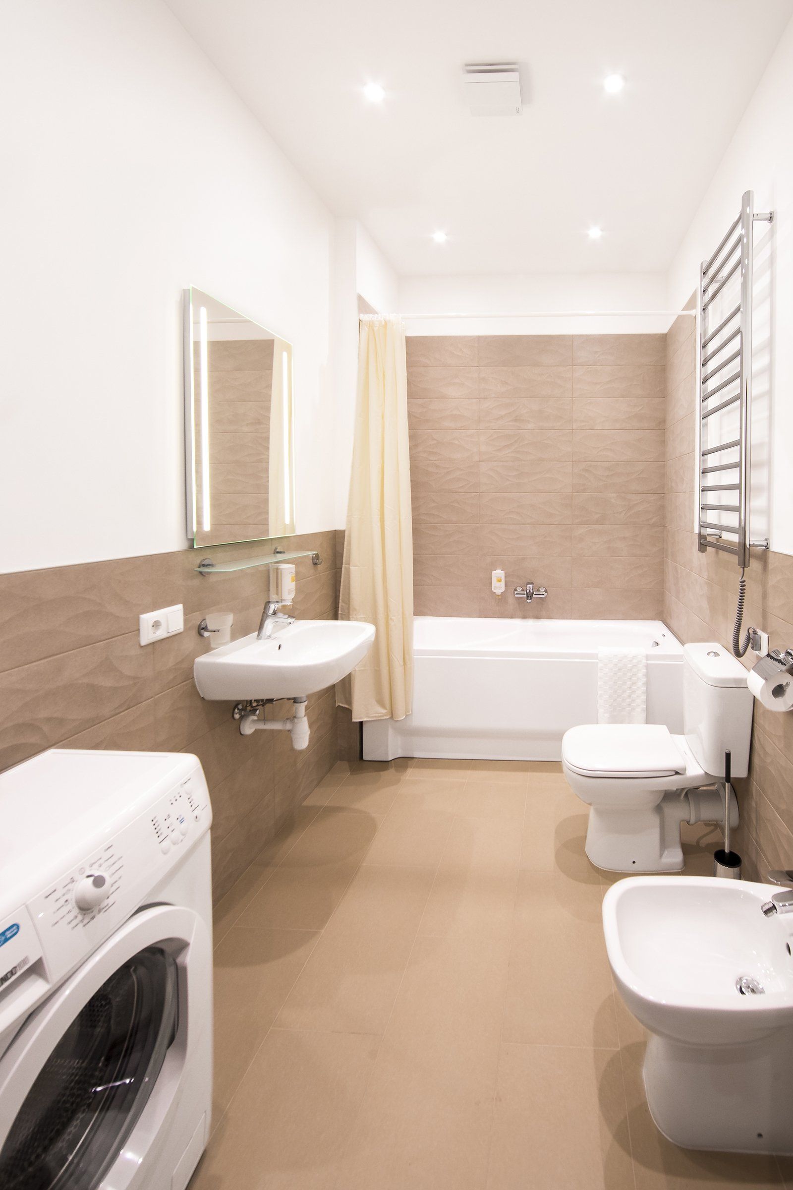 A bathroom with a washing machine , toilet , sink and bidet.
