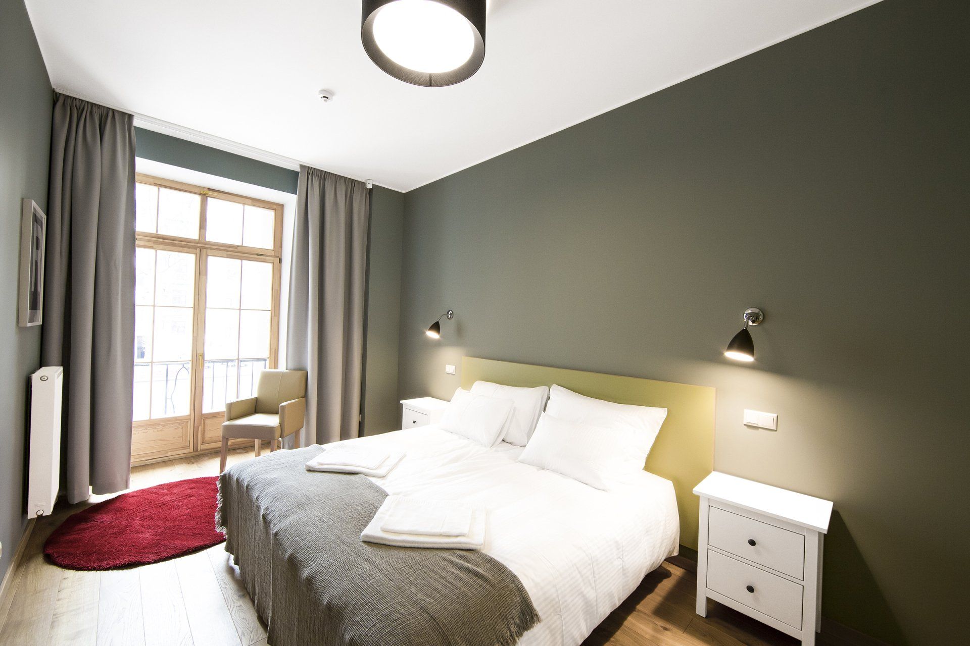A bedroom with a bed , nightstand , chair and window.