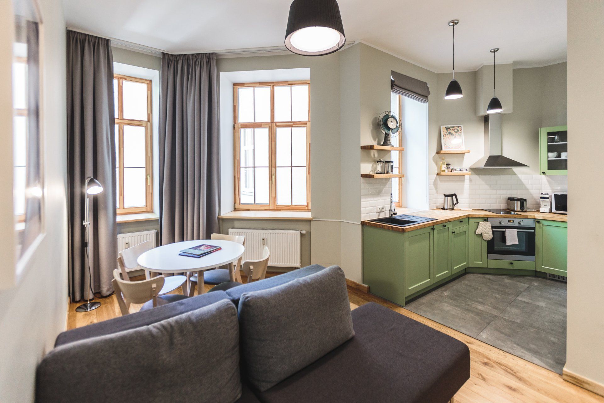 A living room with a couch , table , chairs and a kitchen.