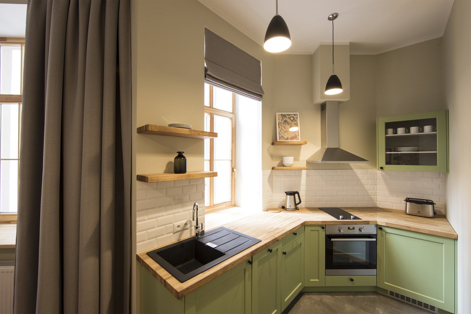 A kitchen with green cabinets , a sink , a stove , and a window.