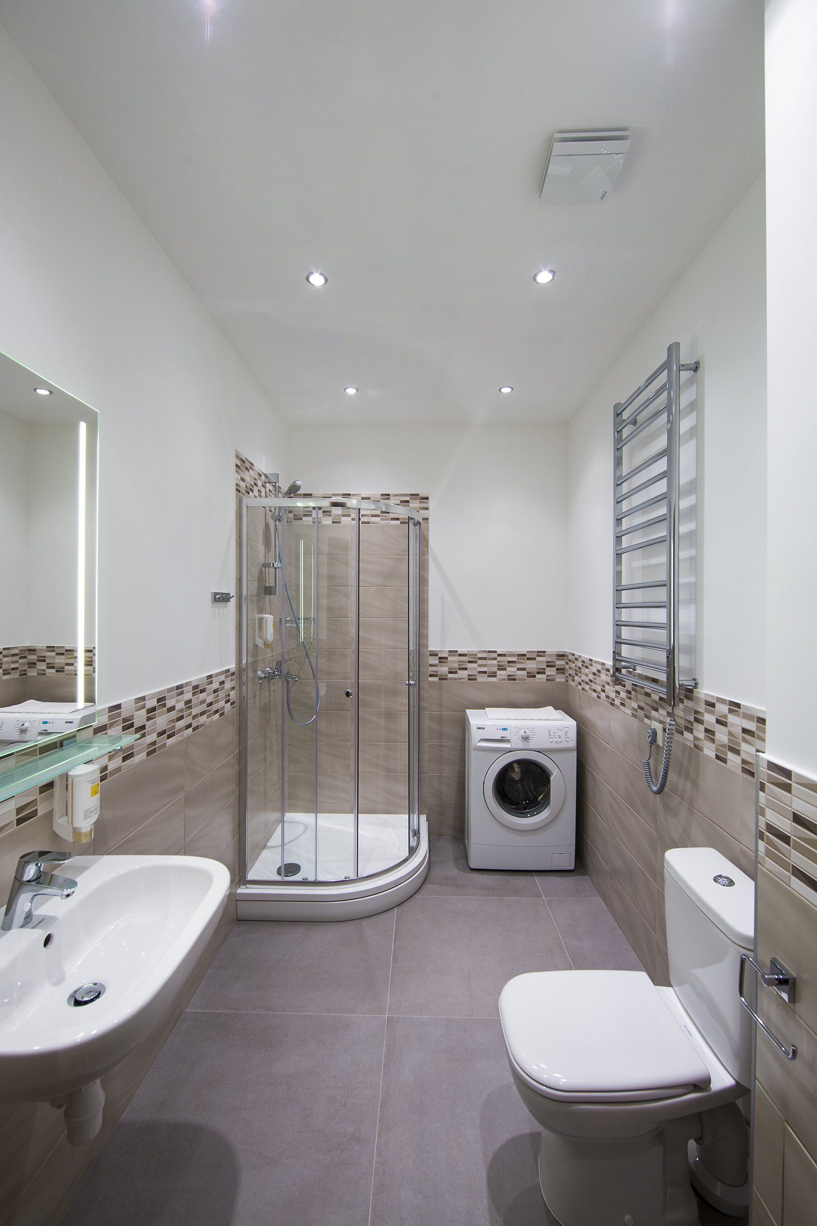A bathroom with a sink , toilet , washer and dryer.