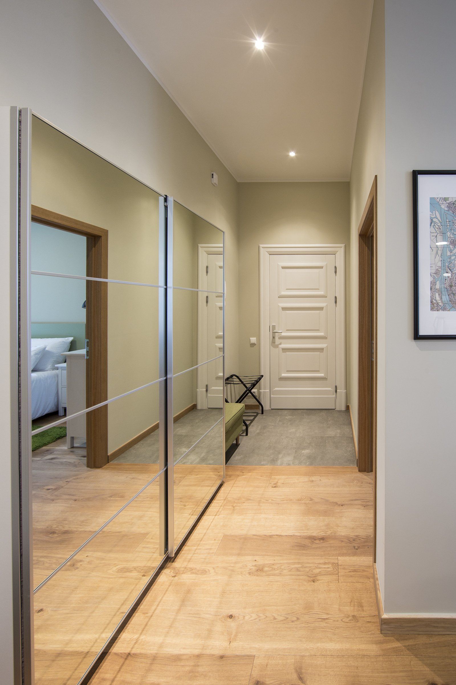 A hallway with a large mirror on the wall and a picture on the wall.