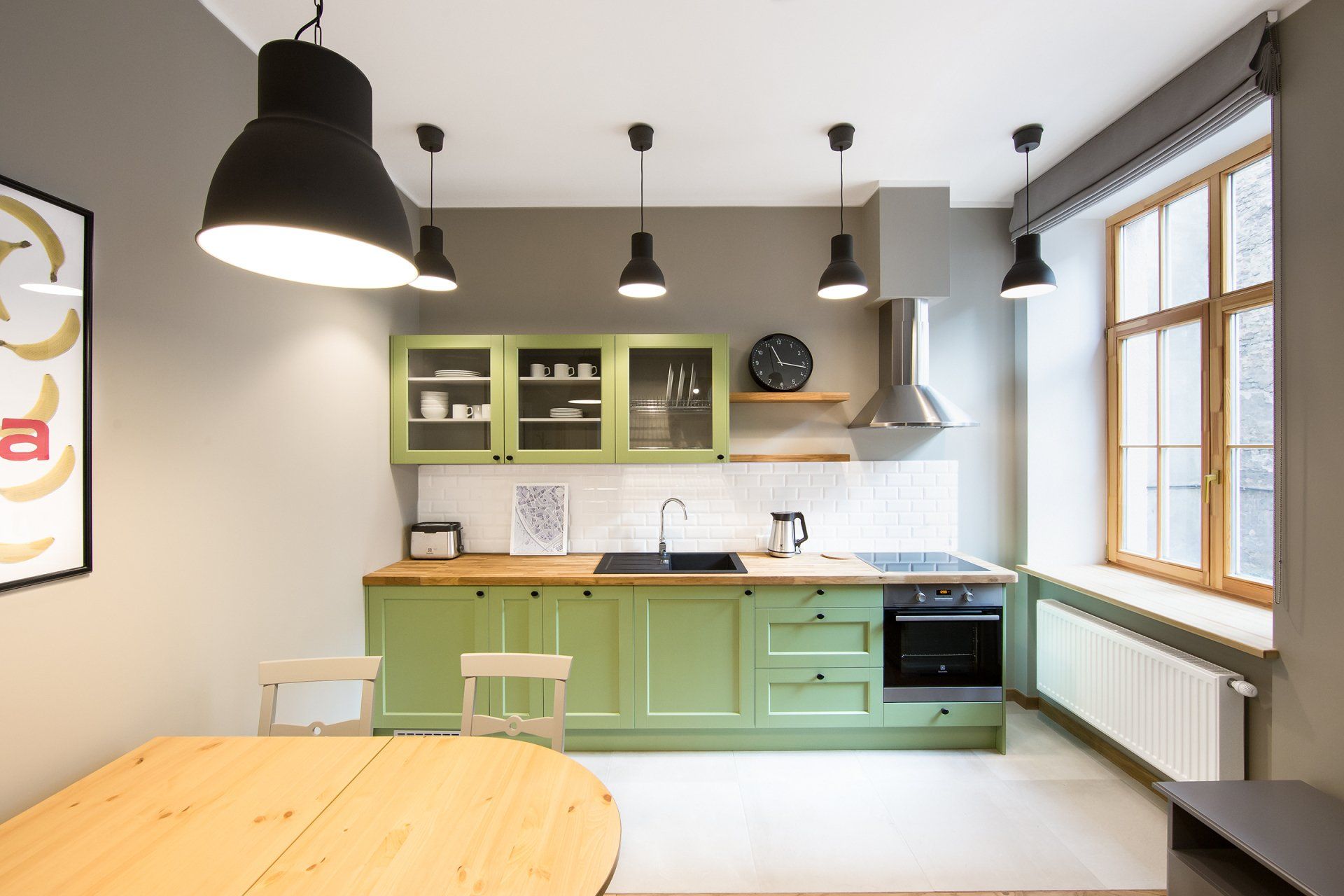 A kitchen with green cabinets and a wooden table.