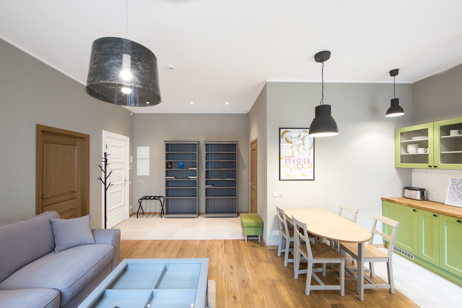 A living room with a couch , table , chairs and a kitchen.