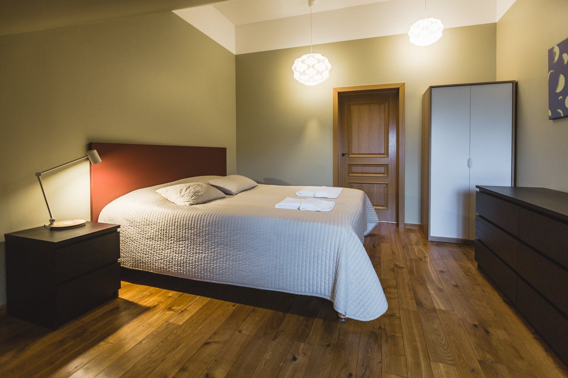 A bedroom with a king size bed , nightstand , dresser and wardrobe.