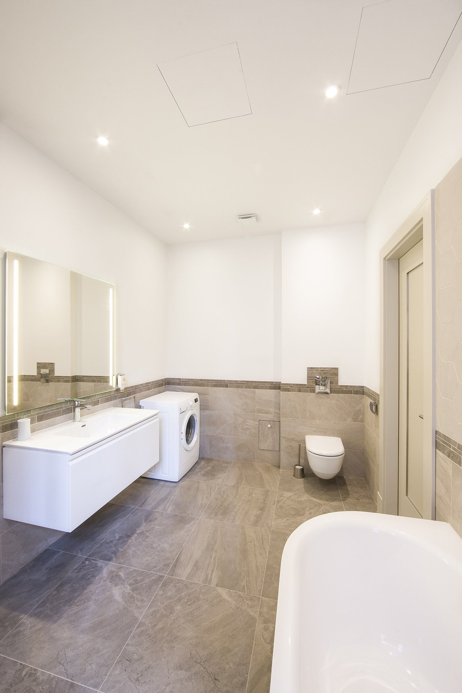 A bathroom with a sink , toilet , washer and dryer.