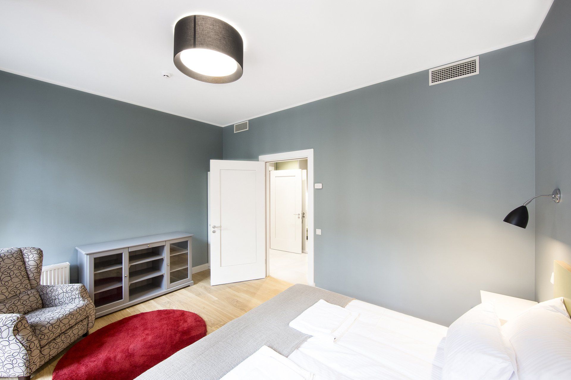 A bedroom with a bed , chair , dresser and rug.