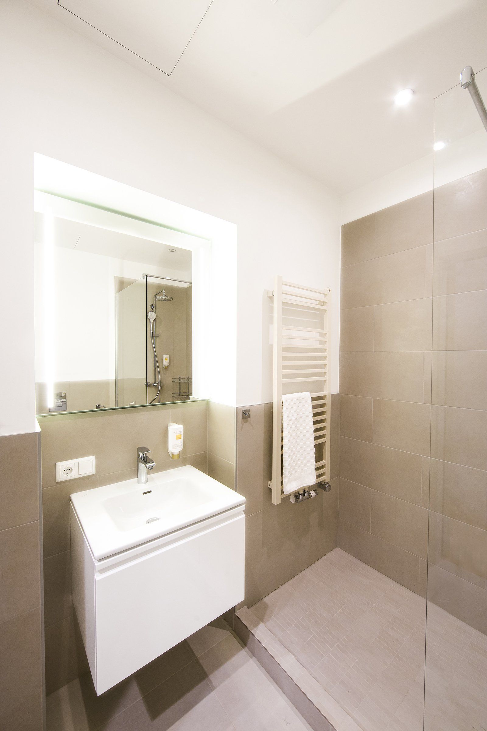 A bathroom with a sink , mirror and shower.