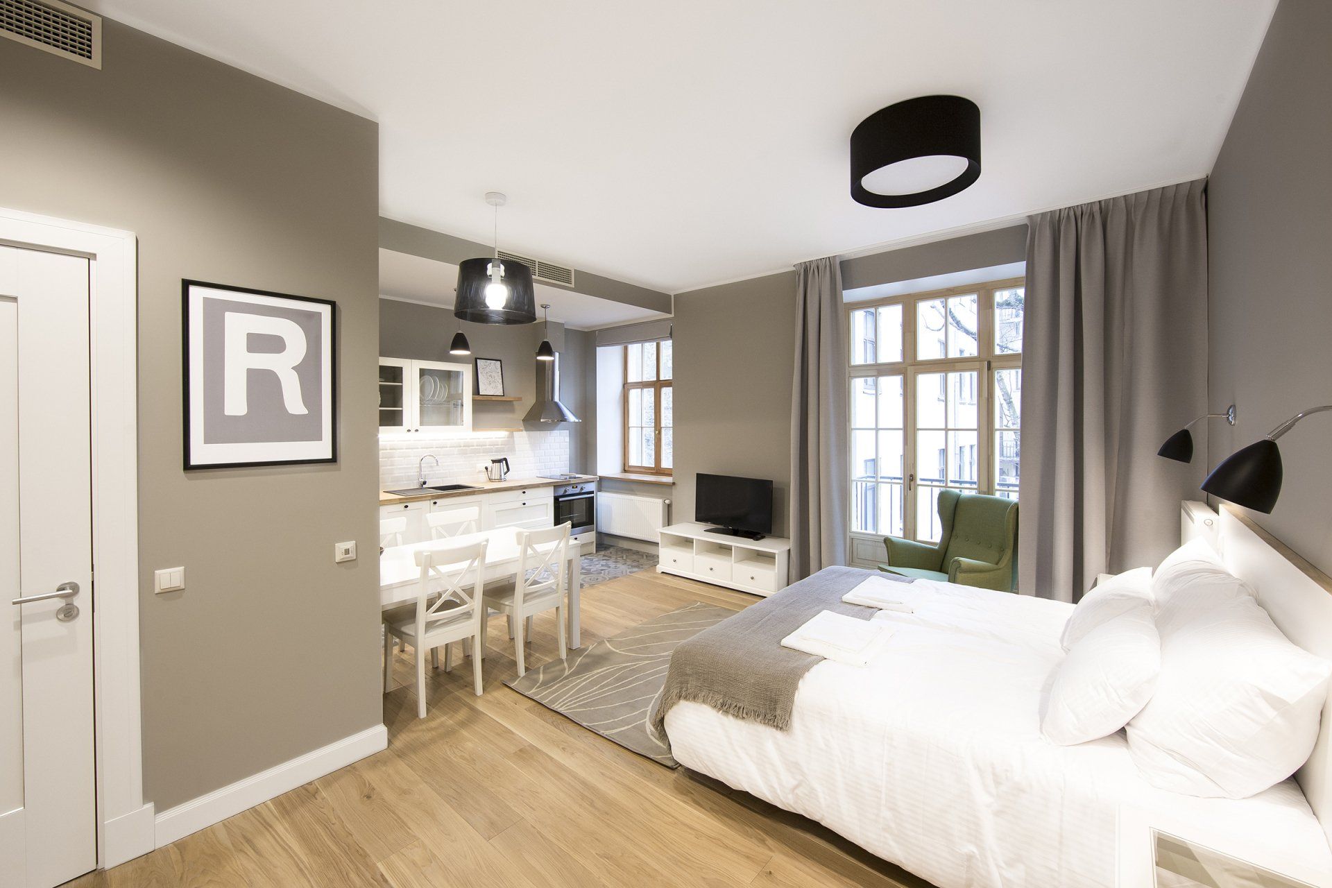 A bedroom with a large bed and a kitchen in the background.