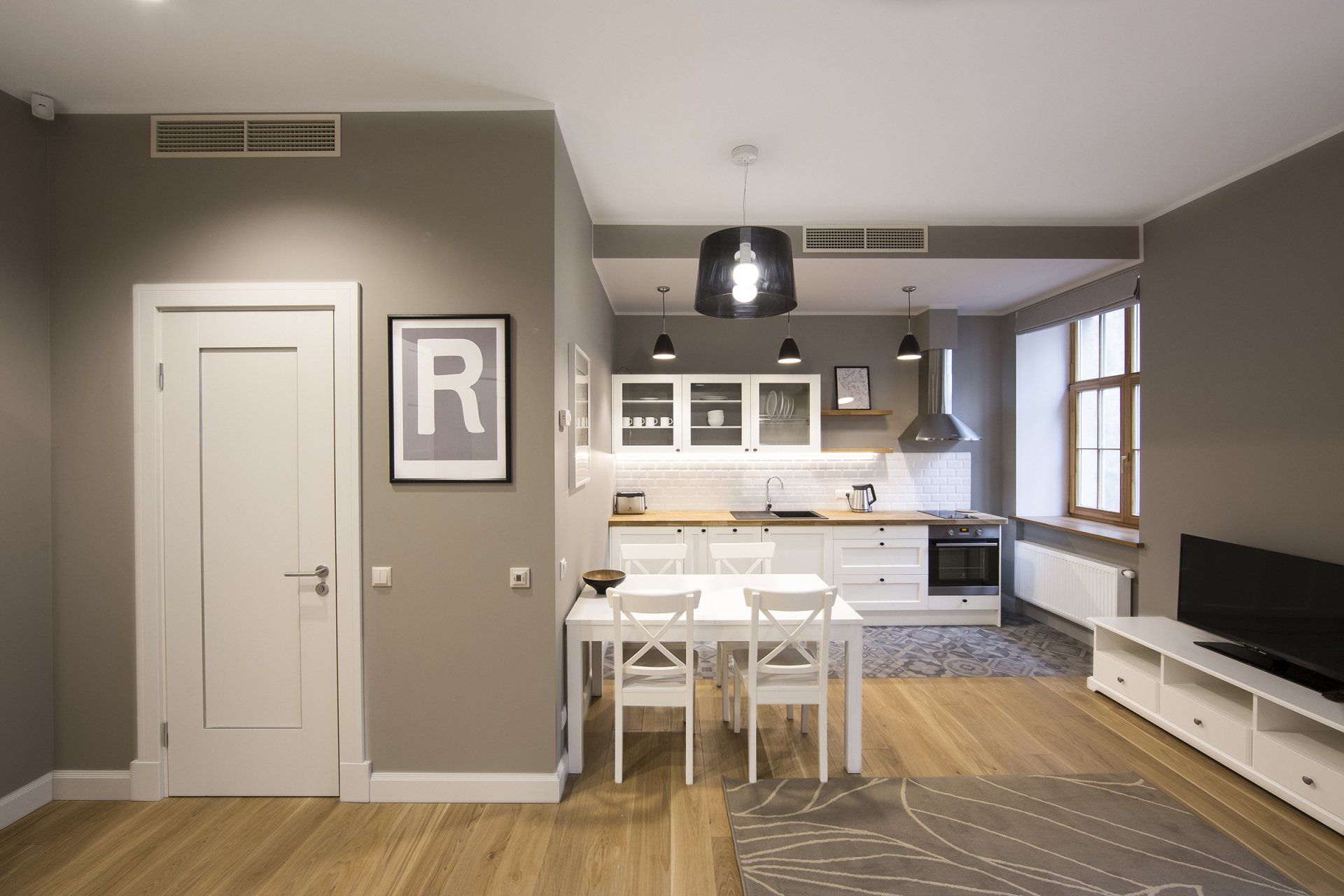 A living room with a dining table and chairs and a kitchen.