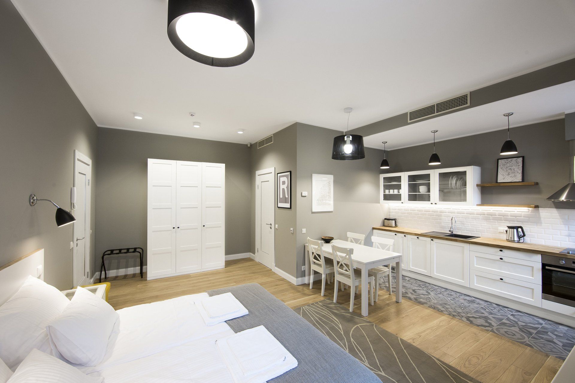 A bedroom with a bed and a kitchen with a table and chairs.