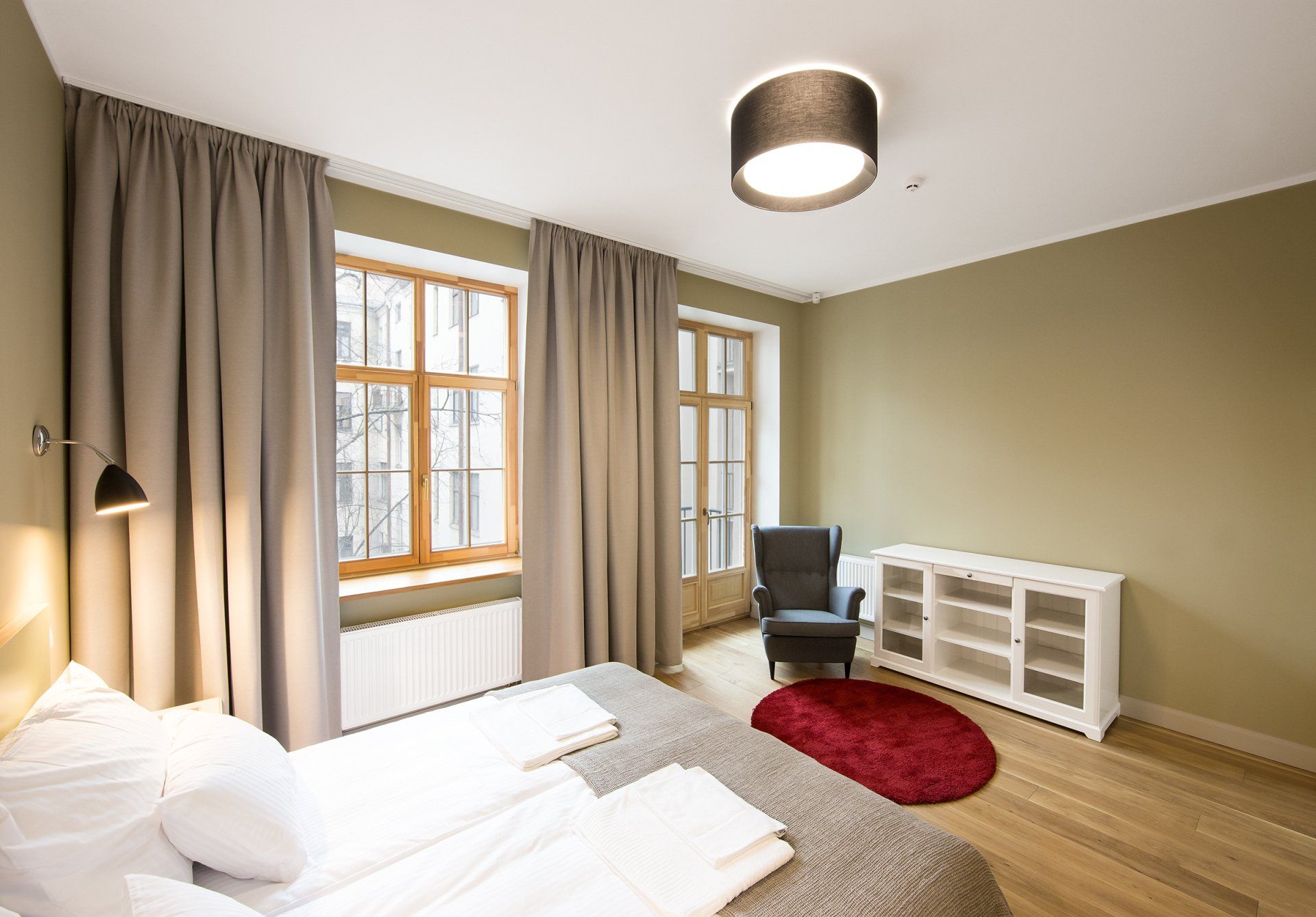 A bedroom with a bed , chair , dresser and window.