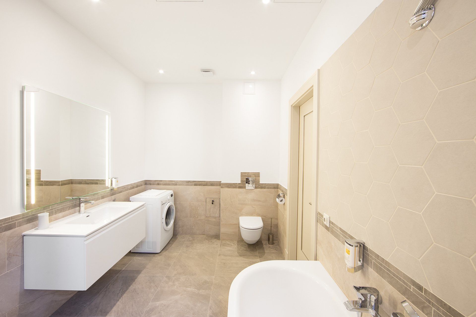 A bathroom with a sink , toilet , washer and dryer.