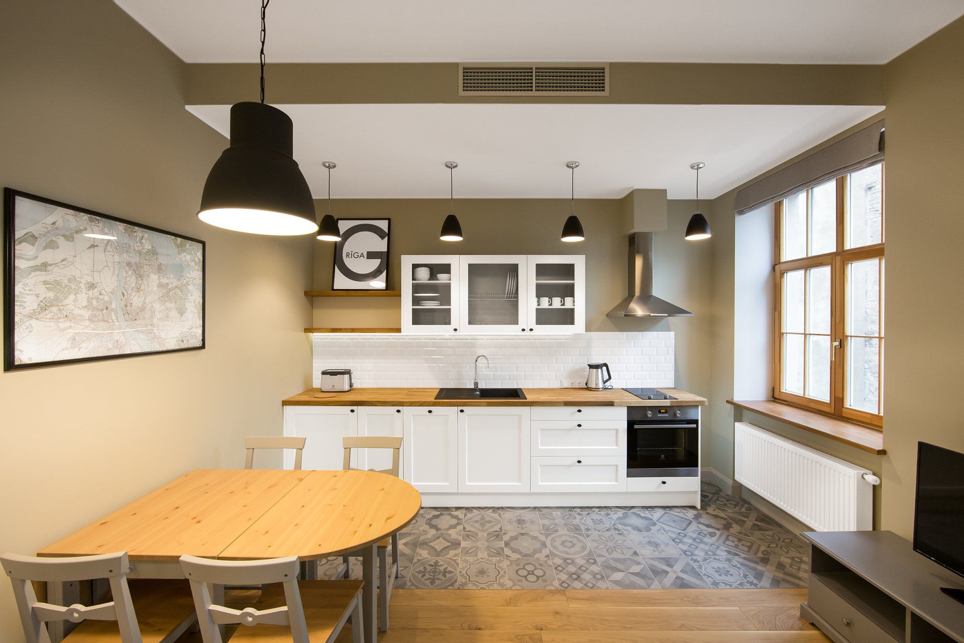 A kitchen with a table and chairs and a television.