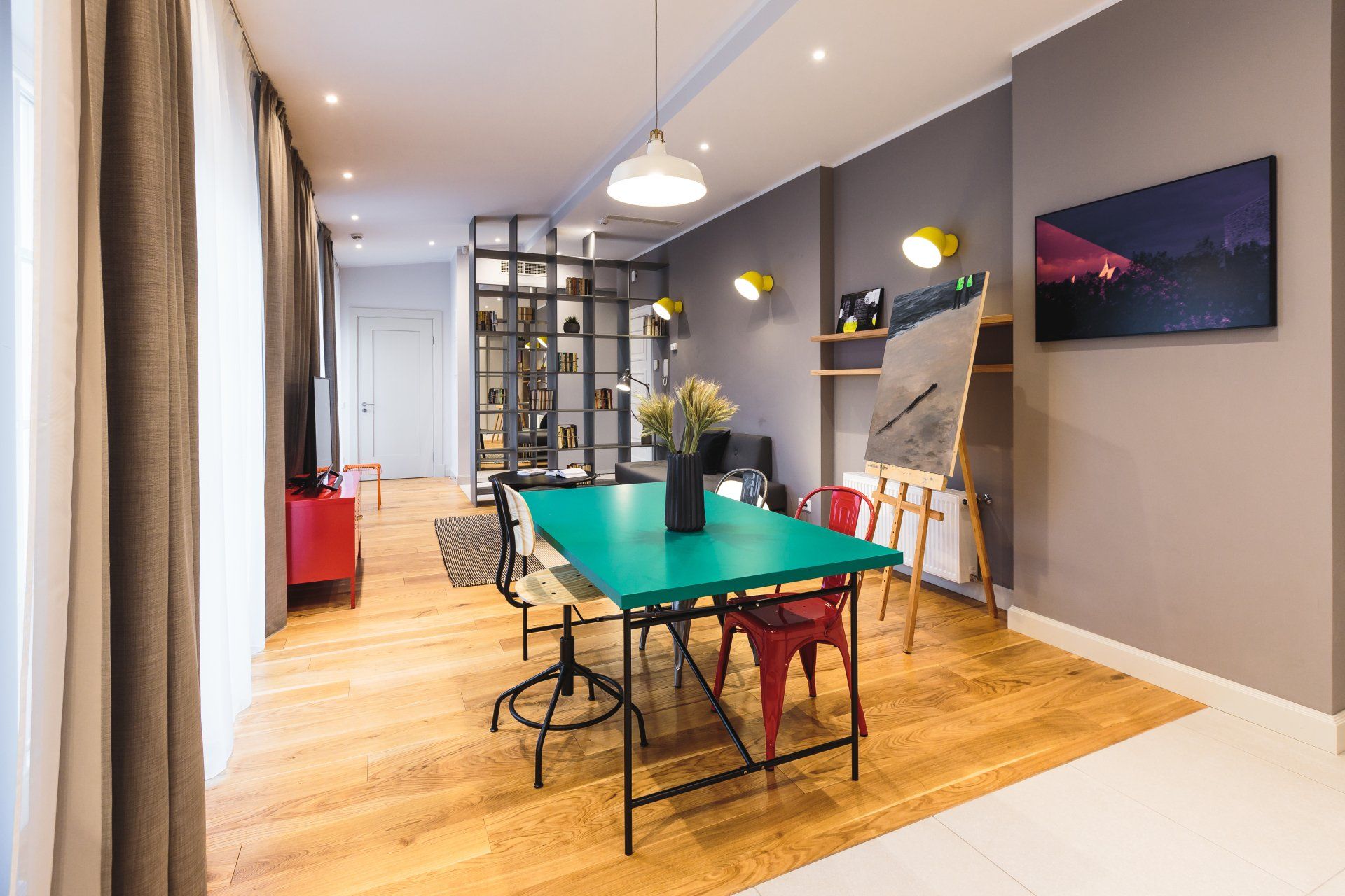 A dining room with a green table and red chairs.