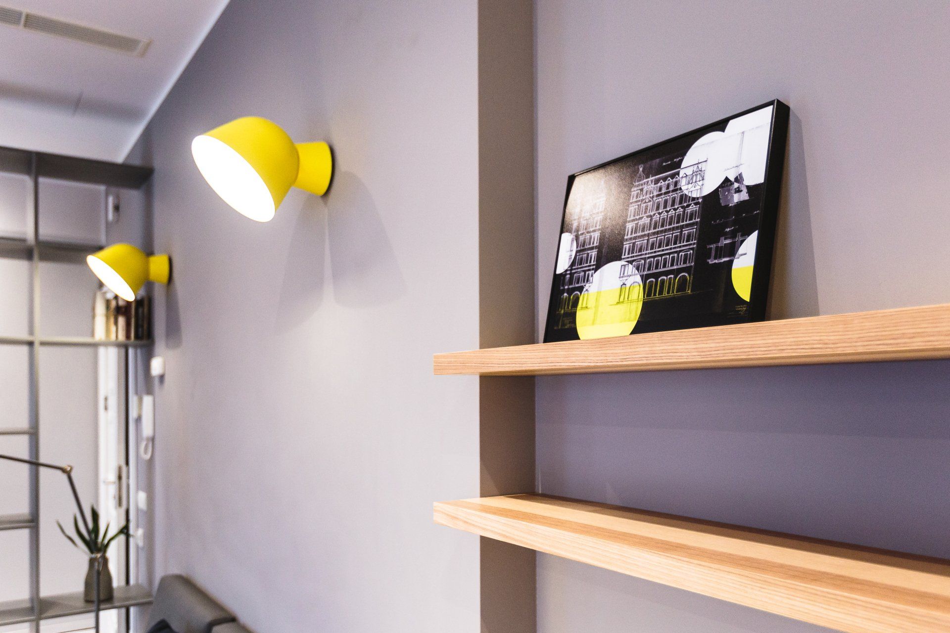 A shelf with a picture on it and a lamp on the wall.