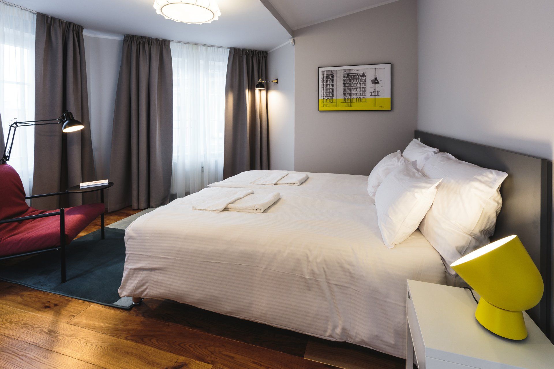 A hotel room with a king size bed and a red chair
